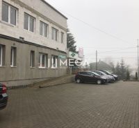 Building on SNP Street in Snina with a parking lot in front of the building and parked cars.