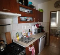Kitchen in a 2-room apartment with dark furniture and kitchen appliances.