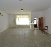 Interior of commercial premises with ceramic flooring, a drawing on the wall, and a chair in the corner.