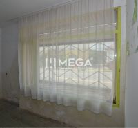 Commercial premises with curtains, a window grille, and worn-out walls.