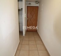 A narrow hallway with tiles and wooden doors in a 3-room apartment.
