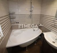 A bathroom in a 3-room apartment with a corner bathtub and a floor with a wooden decor.