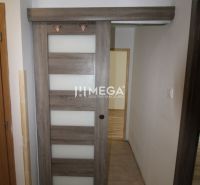 Sliding doors in a 3-room apartment with a wooden decor floor and tiles.