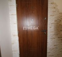 Entrance wooden door in a 3-room apartment with light stone cladding.