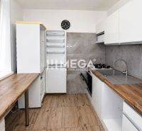 A kitchen in a 3-room apartment with a wooden decor floor and an elegant kitchen unit.
