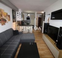 Living room in a 2-room apartment with a corner sofa and a floor with a wooden decor.