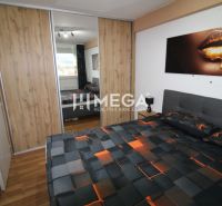 Bedroom with a bed and a wardrobe with sliding doors, floor with wood decor.