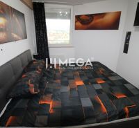 A bedroom in a 2-room apartment with a bed and artistic decorations on the wall.