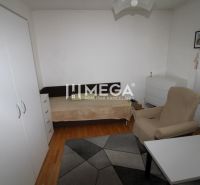 A room in a family house with a bed, an armchair, a table, and a floor with a wooden decor.