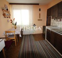 A kitchen in a family house with furniture, a carpet, and a wooden-decor floor.