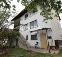 A family house on a street in Snina with two floors, trees, and an outdoor staircase.