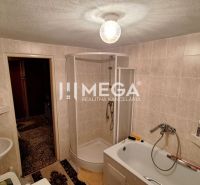 Bathroom in a family house with a bathtub, shower, and sink, tiled with tiles.