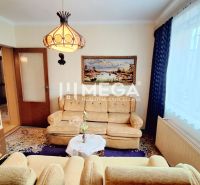 Living room in a family house with a sofa, bookshelf, and curtains.