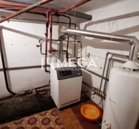 Boiler room with a boiler and piping in a family house, floor with wooden decor.