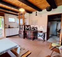 The interior of a cottage with a wooden ceiling, a tiled stove, and rustic furniture.