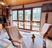 Interior of a cabin with large windows and wooden decor on the walls and furniture.