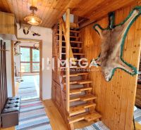 Interior of a cabin with wooden paneling, stairs, and a kitchen unit, complemented by decorative fur.