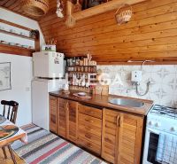 A kitchen in a cottage with a wood-patterned floor, wooden cabinets, and a dining table.