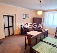 A room in a family house with a stove, a table, and a bed, with a wooden decor floor.