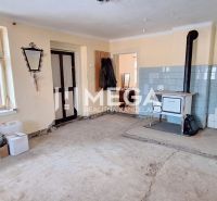 Interior of a family house with a tiled stove and a wallpapered wall on a floor with a wooden decor.