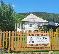 The family house for sale in the village of Kochanovce stands behind a fence with greenery.