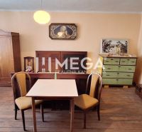 A room in a family house with a wooden decor floor, a table, chairs, and antique furniture.