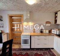 A kitchen in a family house with a carpet, kitchen unit, and curtains by the table.