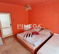 A bedroom in a 2-room apartment with orange walls and a floor with a wood decor.