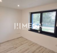 A room in a family house with a wooden decor floor and a large window.