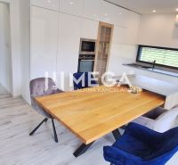 A kitchen in a family house with a wooden decor floor, built-in appliances, and a dining table.