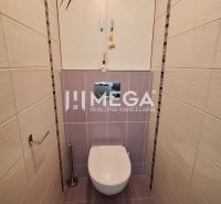 A toilet in a 3-room apartment with light ceramic tiles and a wall cabinet.