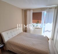 A bedroom with a large bed, wardrobe, and wooden decor flooring in a 3-room apartment.