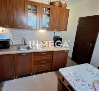 A kitchen in a 3-room apartment with wooden cabinets and a dining table.