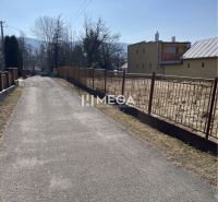 The road by the residential plots in Modra nad Cirochou, surrounding houses and greenery.