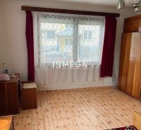 A room in a family house with a wooden decor floor, red curtains, and cabinets.