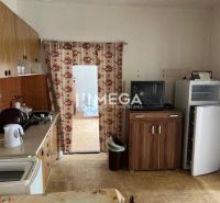A kitchen in a family house with a wooden decor floor, containing older furniture.