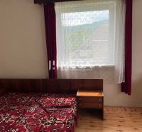 Bedroom in a family house with a bed, window, red curtains, and a wooden decor floor.