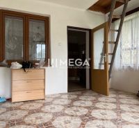 A room in a family house with a ceramic floor and stairs, wooden doors and windows.