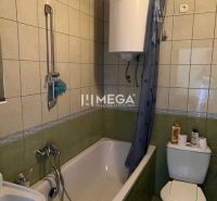 A bathroom with a bathtub and toilet tiled with green tiles in a family house.