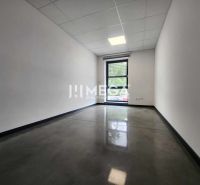 The interior of an office with a window, white walls, and a dark floor.