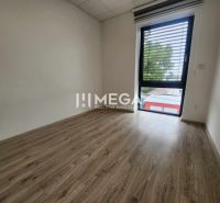 An office with a wood-patterned floor and a large window, simple interior.