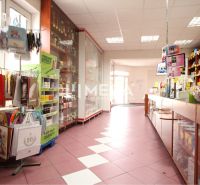 Retail space with shelves and goods, floor with wooden decor, strong lighting.