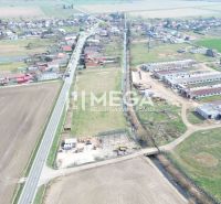 Aerial view of manufacturing facilities in the village of Hriadky surrounded by agricultural fields and a road.