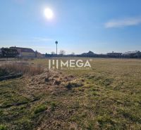 Production facilities in Hriadky, grassy area and buildings with a clear sky.