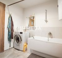 A bathroom in a family house with a washing machine, bathtub, mirror, and curtain.