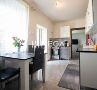 A kitchen in a family house with a dining table, flowers, and appliances.