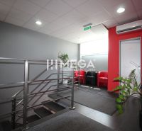 The staircase leading to the offices, with plants and red chairs in the interior.