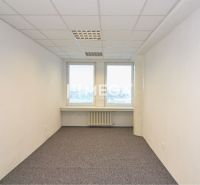 Interior of an office with white walls, carpet, and two windows.