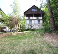 A cottage in Holčíkovce surrounded by greenery with a stone facade and wooden balconies.