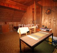 The interior of a cabin with wood-paneled walls, carpeted floor, and a table with two chairs.